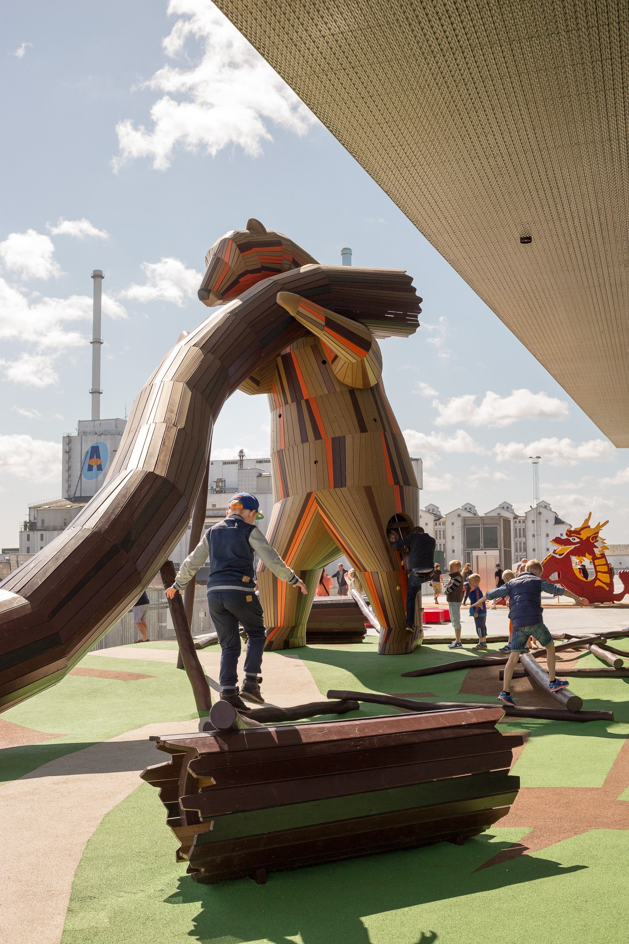 Children playing on a large wooden troll sculpture at Dokk1 library's playground in Aarhus.