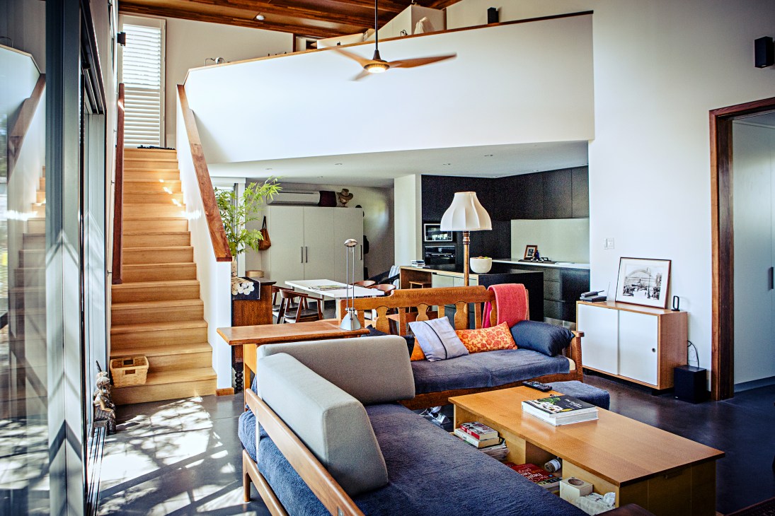 Open-plan interior of The Boathouse featuring wooden stairs, modern kitchen, and lounge area with blue sofa.