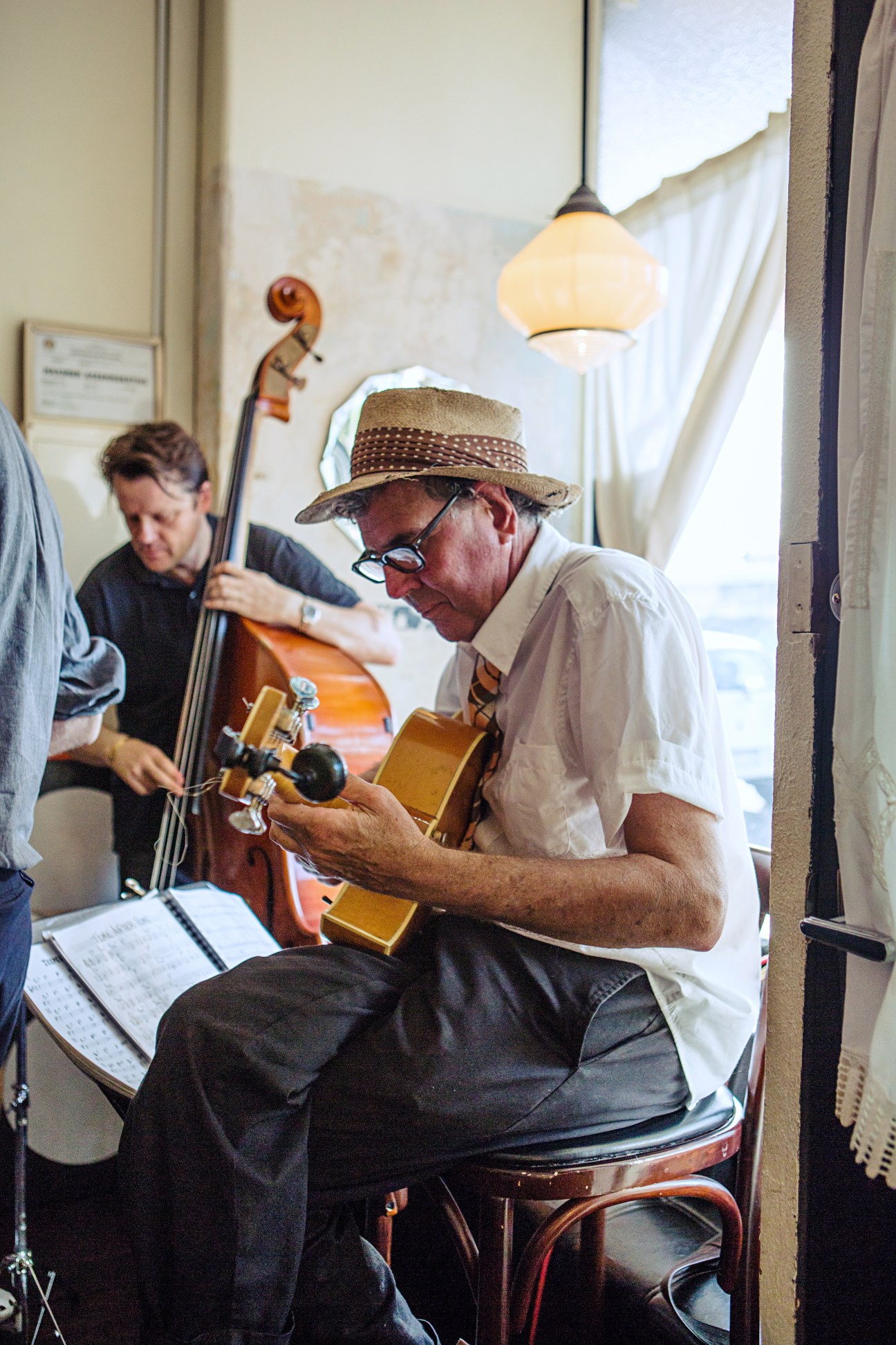 Musicians performing jazz at Swallow Bar, with guitarist in straw hat and bassist in background.