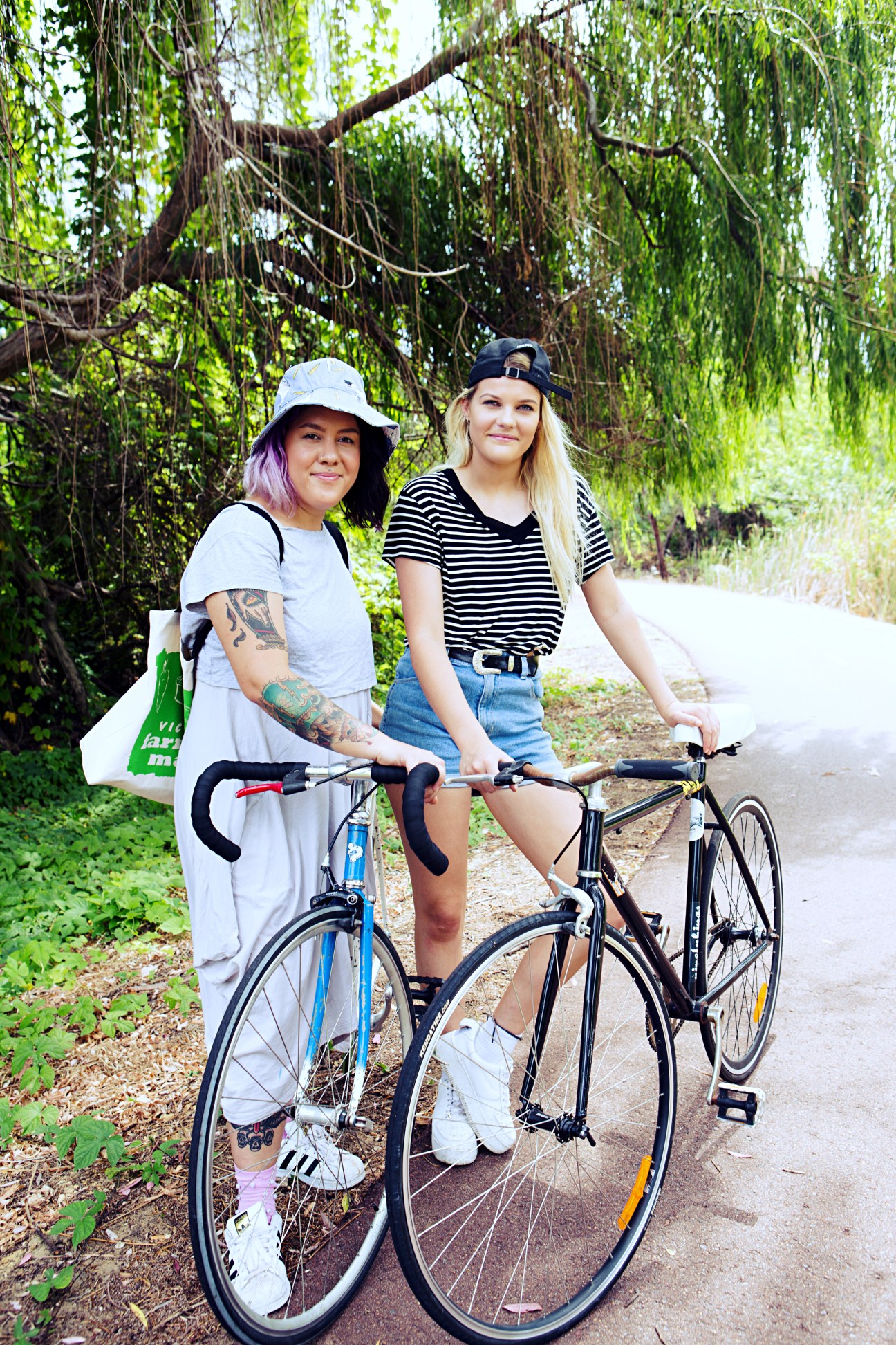 Two women with bicycles on a tree-lined path in Maylands, Perth.