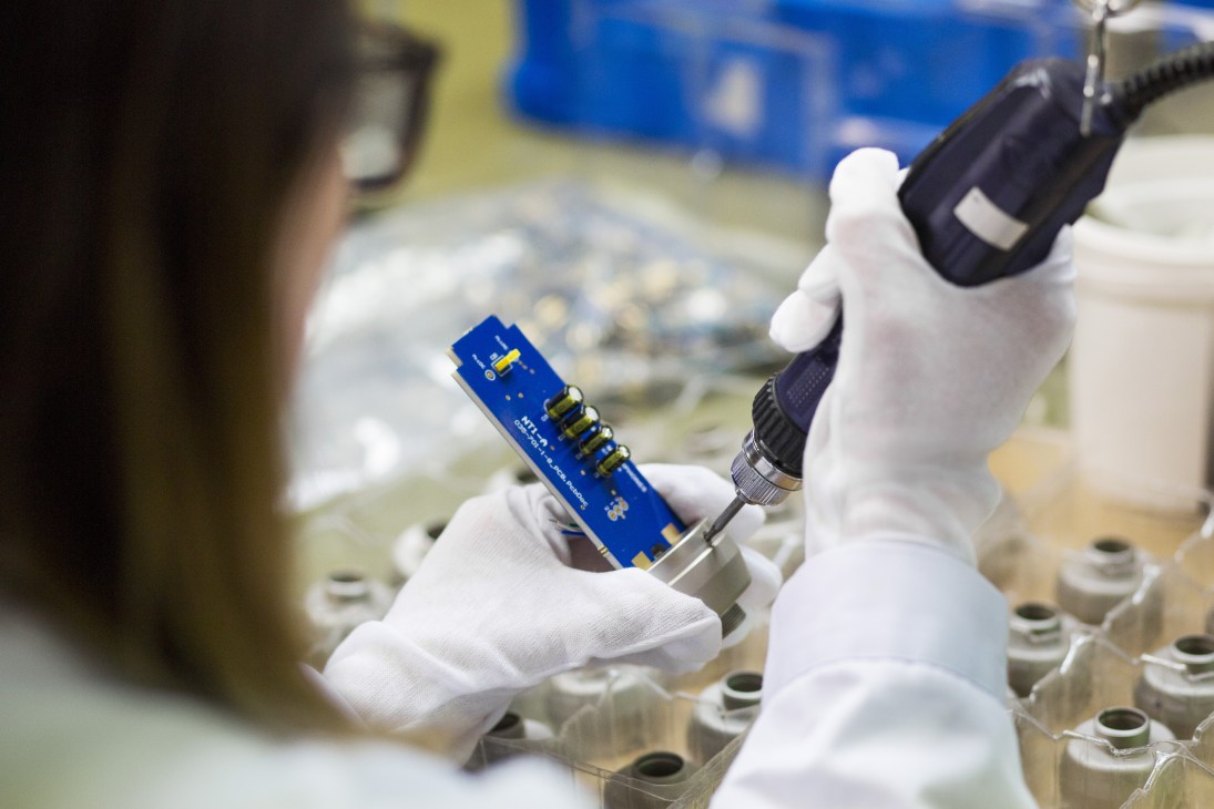 Worker in white gloves assembling a Røde NT1-A microphone circuit board at the company's Sydney headquarters.