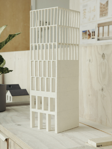 White architectural model of a tall tower building displayed in a studio setting