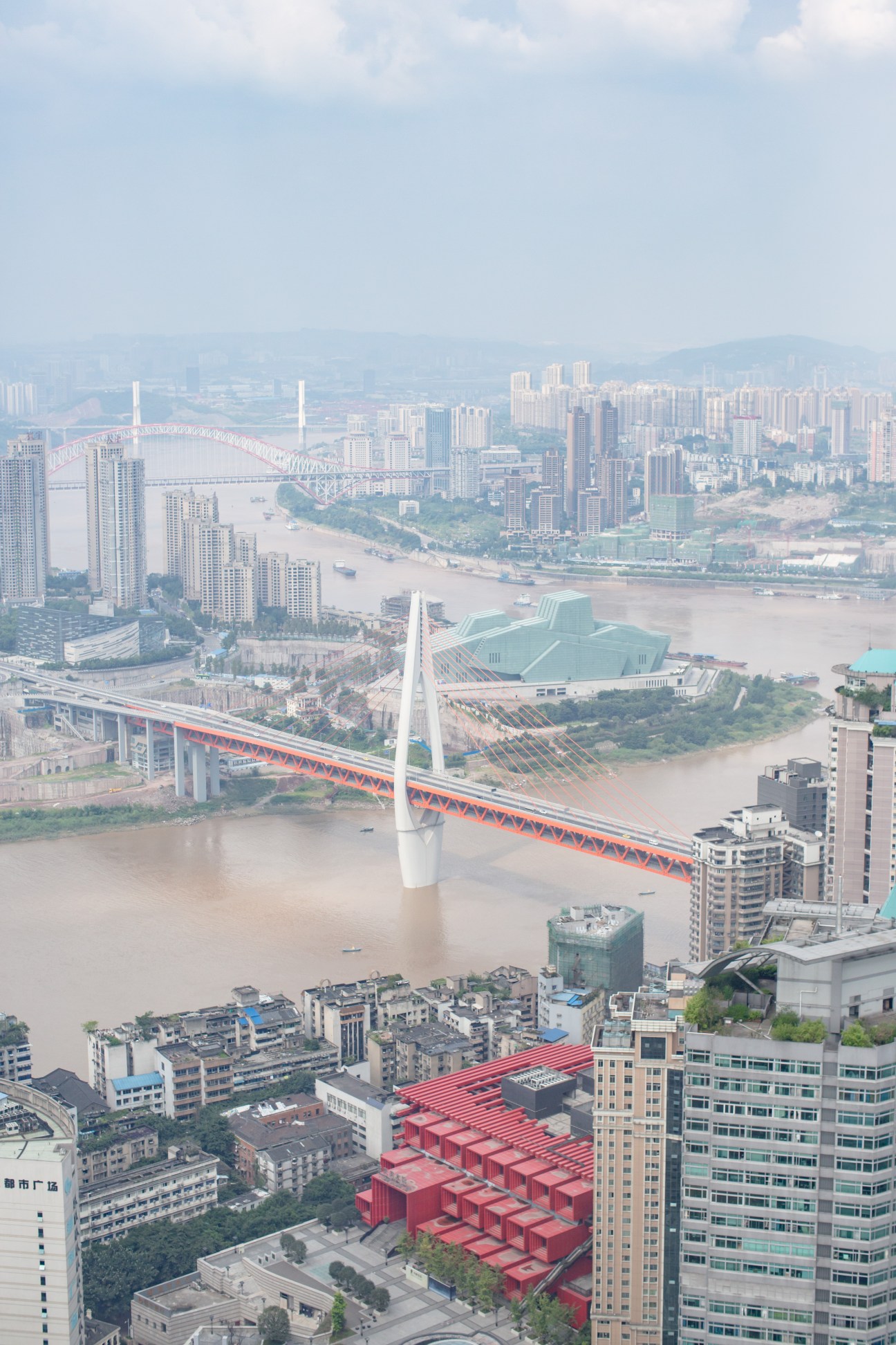Aerial view of Chongqing showing where the Jialing and Yangtze rivers meet, with bridges, high-rises and the distinctive green theatre building.