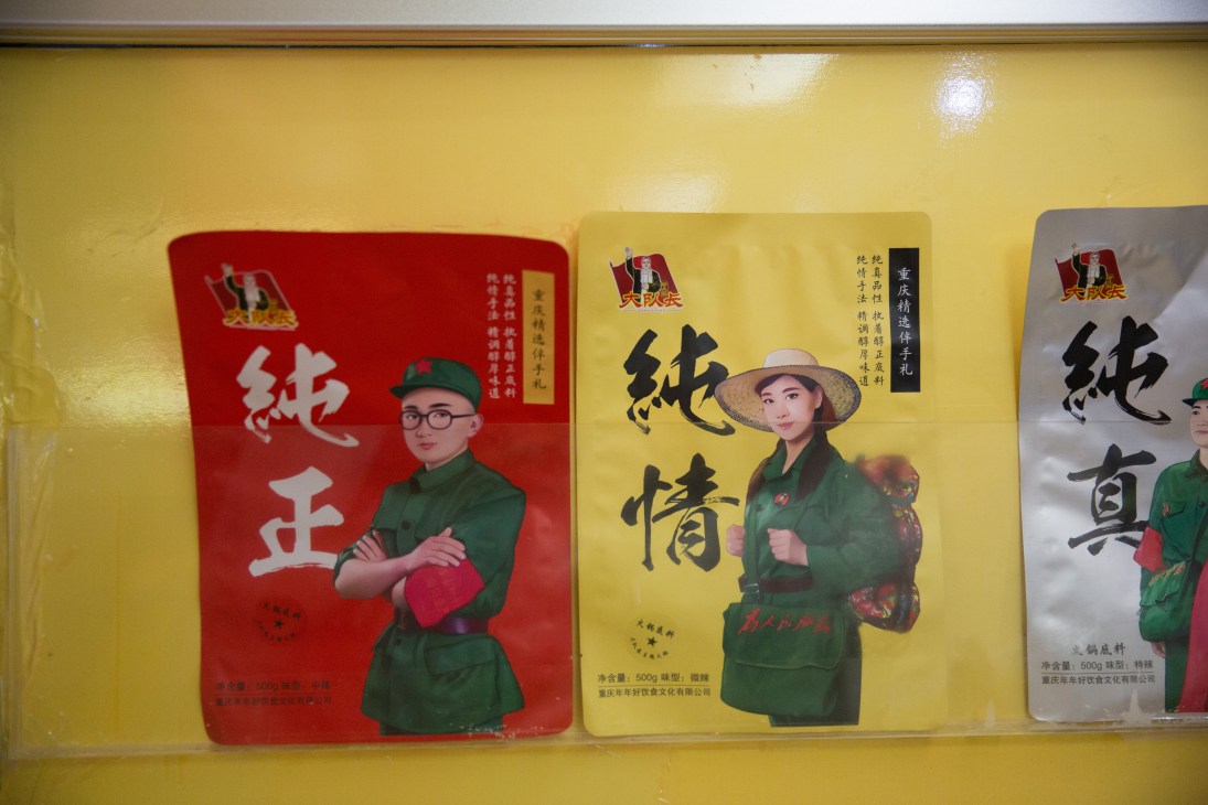 Packets of stock displayed on a yellow shelf at Big Squad Captain restaurant featuring Maoist-era imagery and figures
