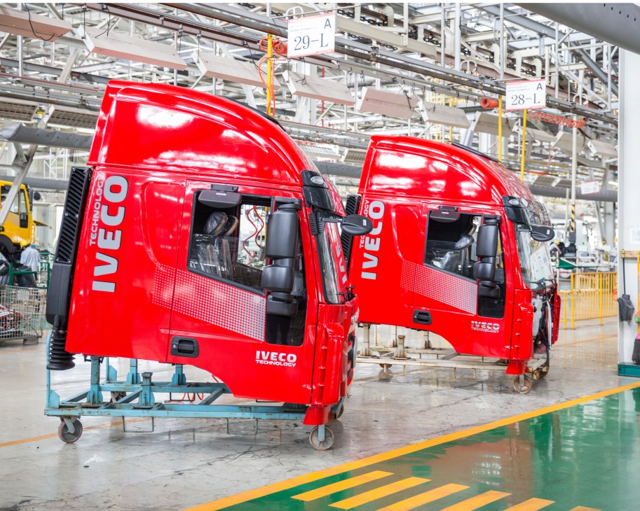 Two red Iveco trucks prepared at a factory assembly line in Chongqing.