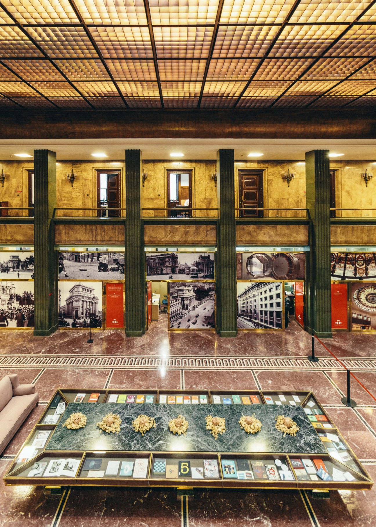 Madrid Instituto Cervantes lobby with ornate ceiling, columns, and cultural display cases.