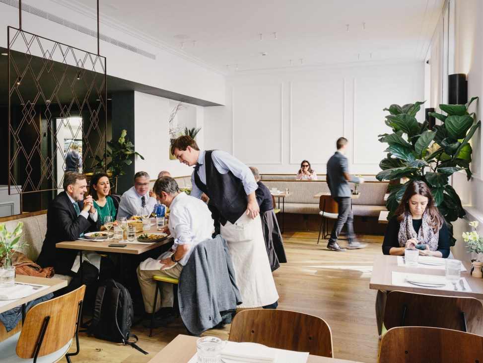 Diners seated at tables during lunchtime service at Hermosos & Malditos restaurant in Madrid.