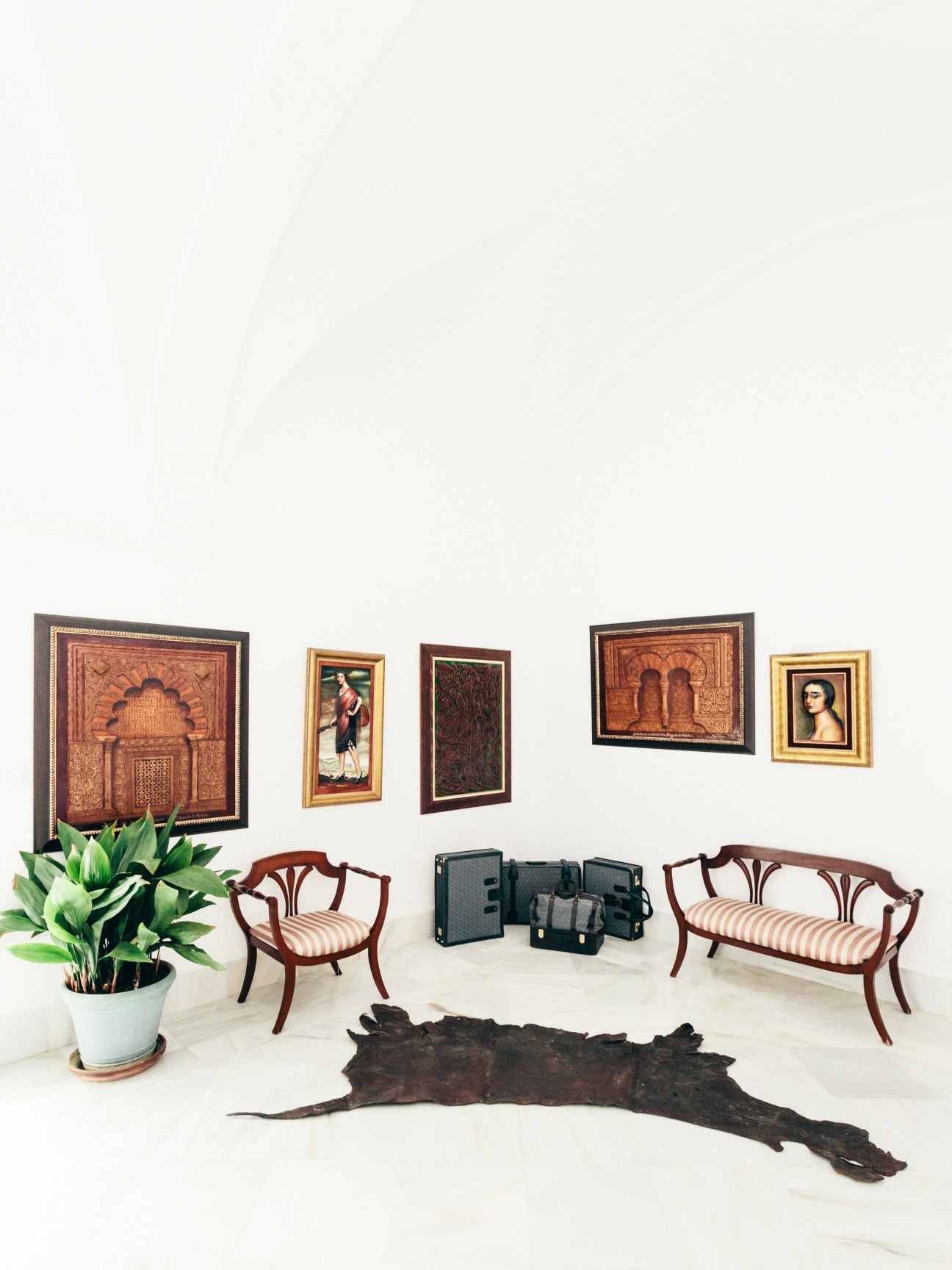 Museum display featuring framed leather artworks, wooden furniture, leather goods, and a raw hide on white flooring.
