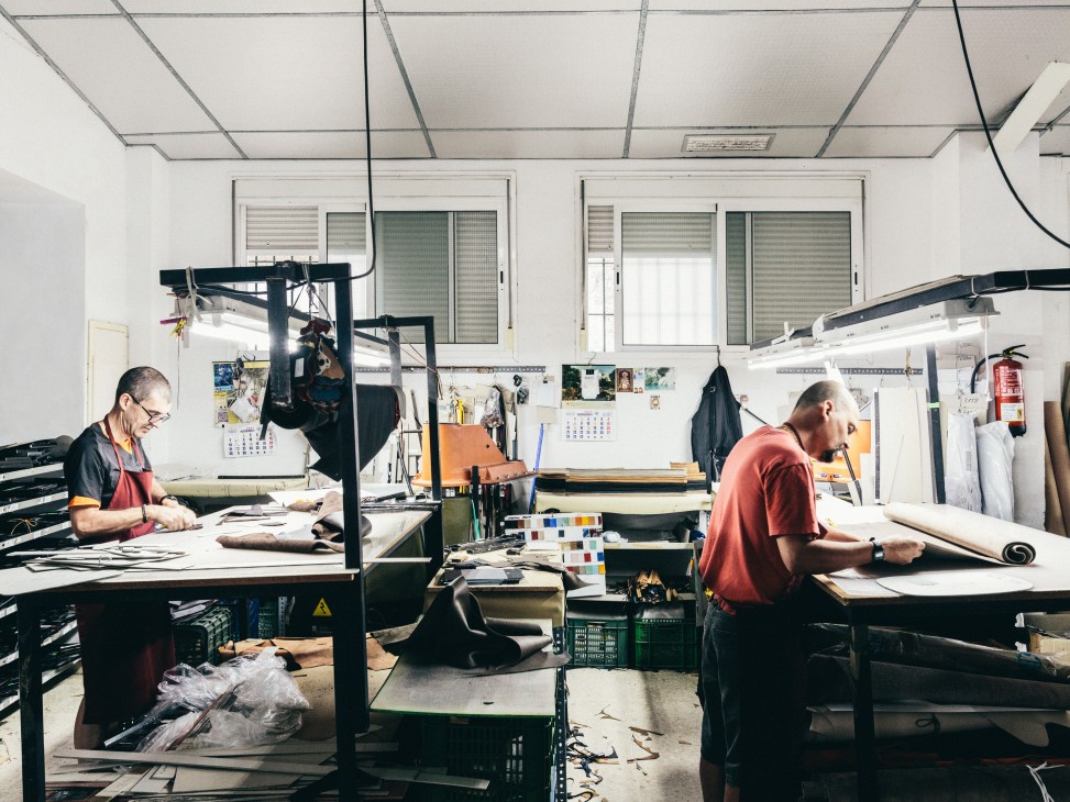 Workers at Carla Sade leather factory in Ubrique, Spain, crafting leather goods at workstations.
