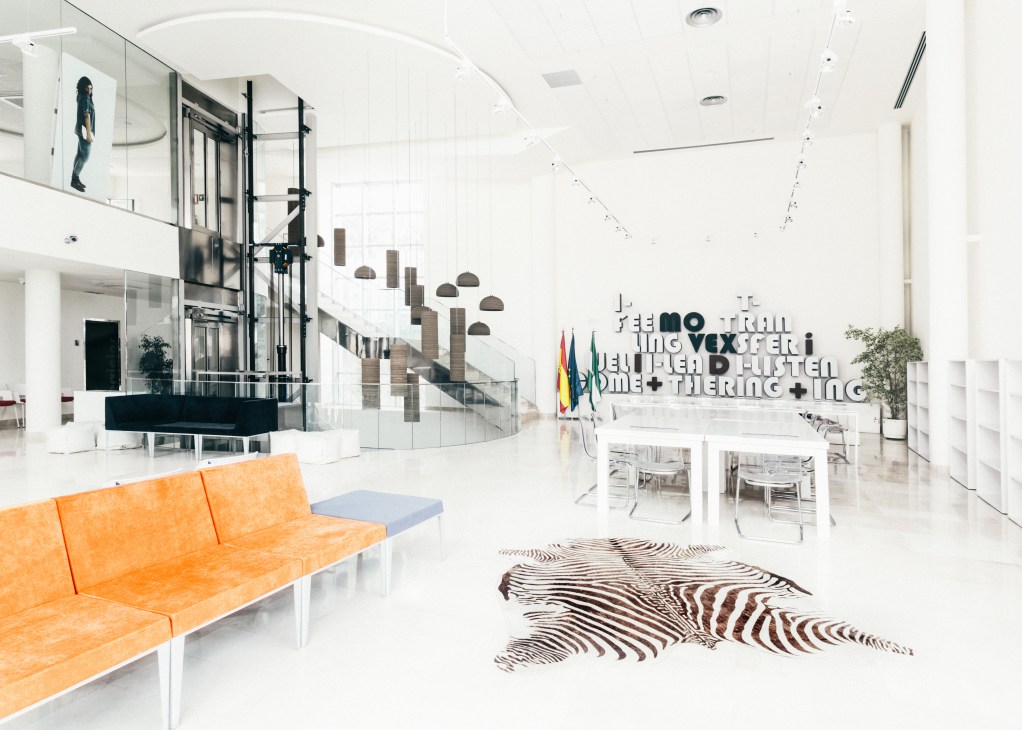 Movex innovation center lobby with modern white interior, orange seating, and zebra hide rug.