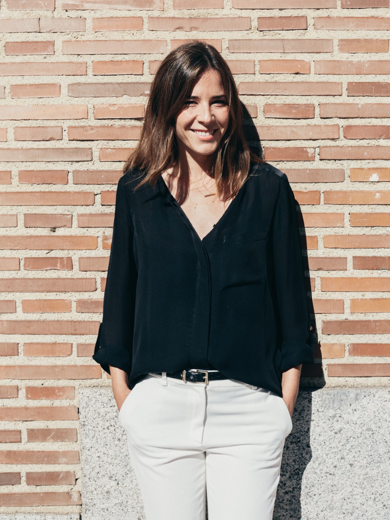 Leticia de la Cuesta Ruíz-Larrea of La Portegna smiling against a brick wall.