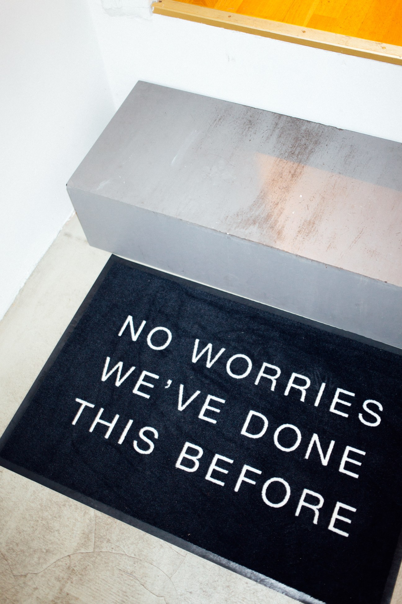 Black doormat with white text reading "NO WORRIES WE'VE DONE THIS BEFORE"