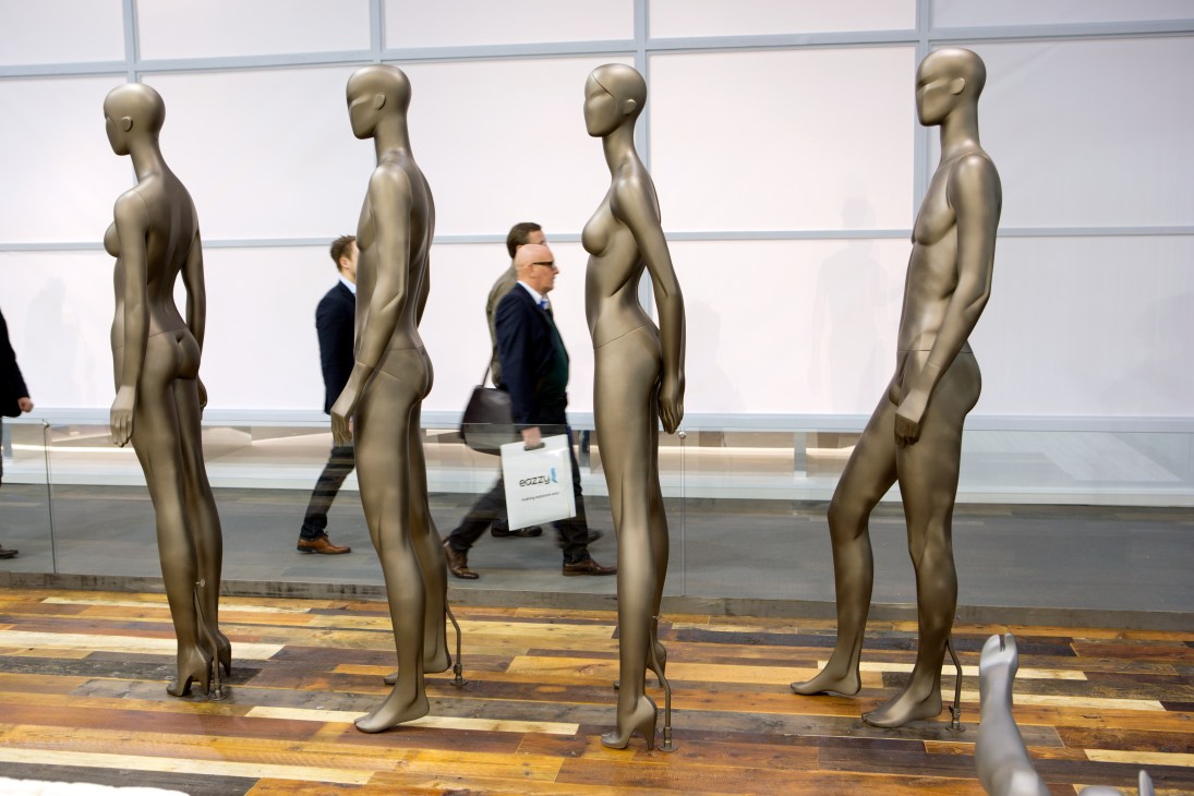 Visitors walk past gold-finished mannequins with magnetic joints at Vision Fashion Mannequins' EuroShop stall.