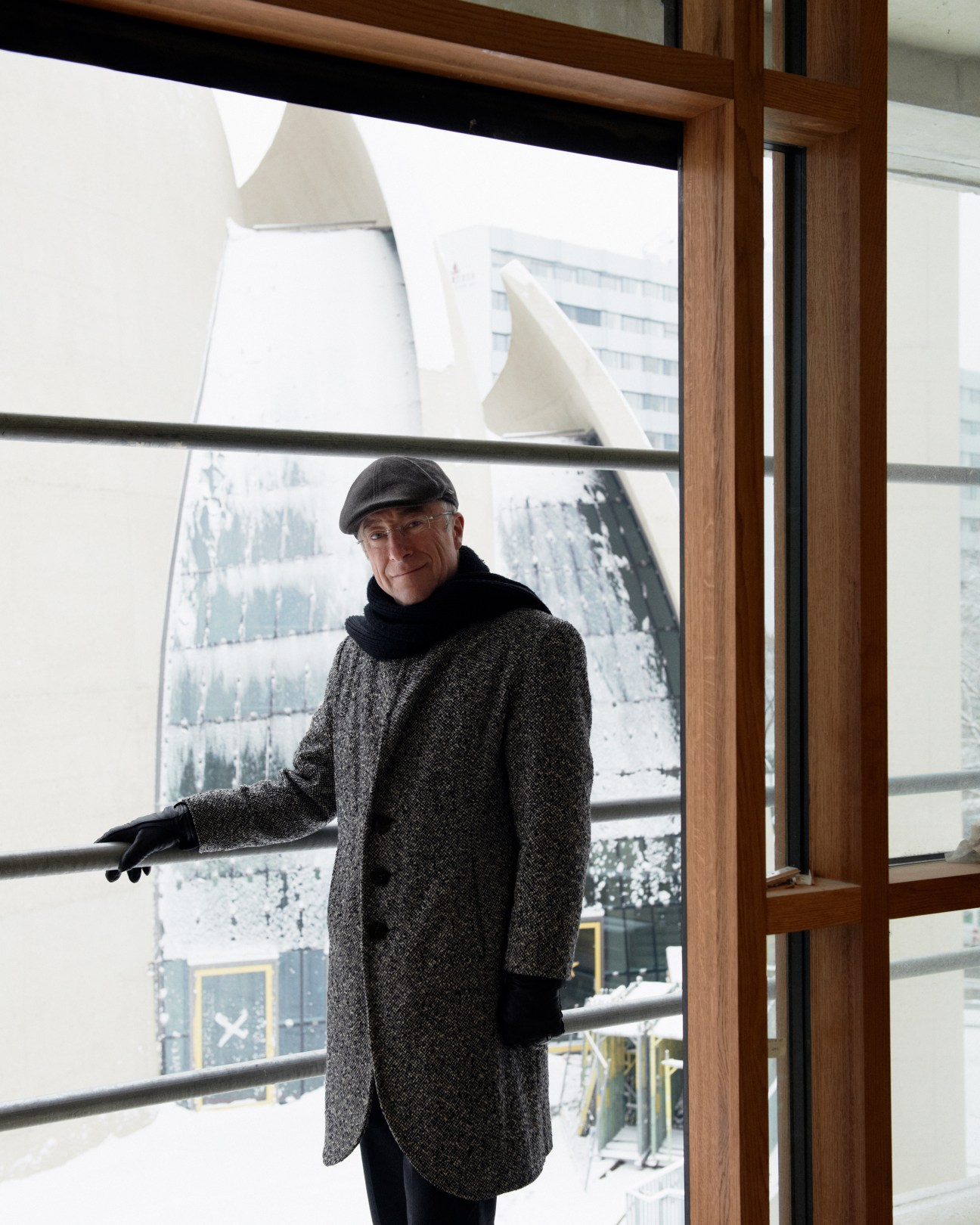 Paul Böhm, architect, standing by a window with snow-covered concrete building visible behind him.