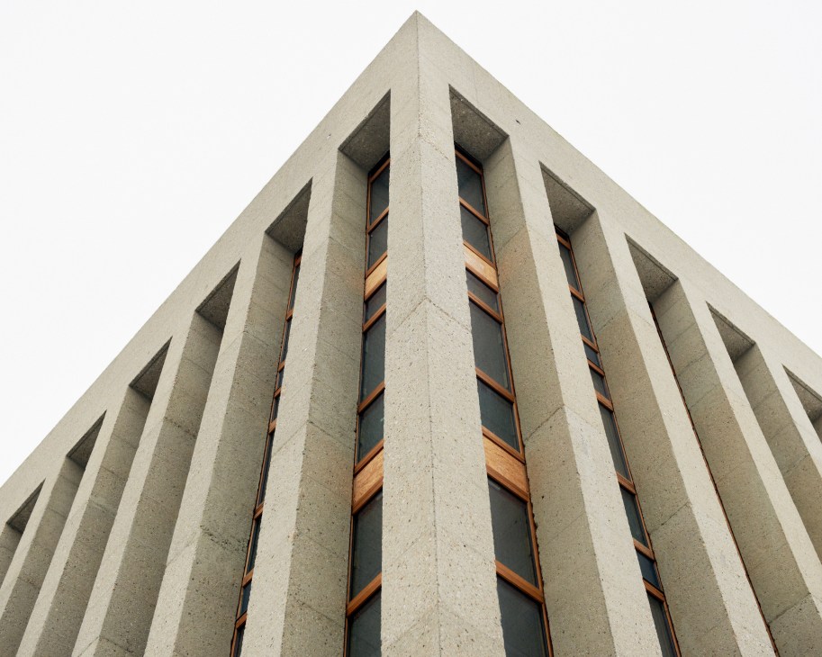 Raw concrete façade of the Central Mosque with vertical ribbed panels and wooden-framed windows.