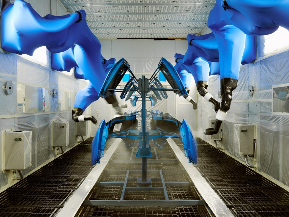 Robotic arms wrapped in protective blue stockings inside a painting tunnel at BMW's Leipzig factory.