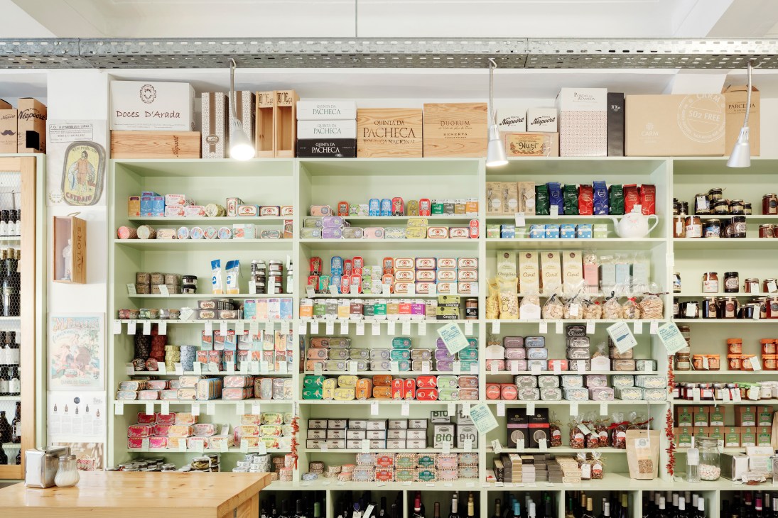 Interior of Mercearia das Flores showing pale green shelving packed with Portuguese food products, wines and artisanal goods.