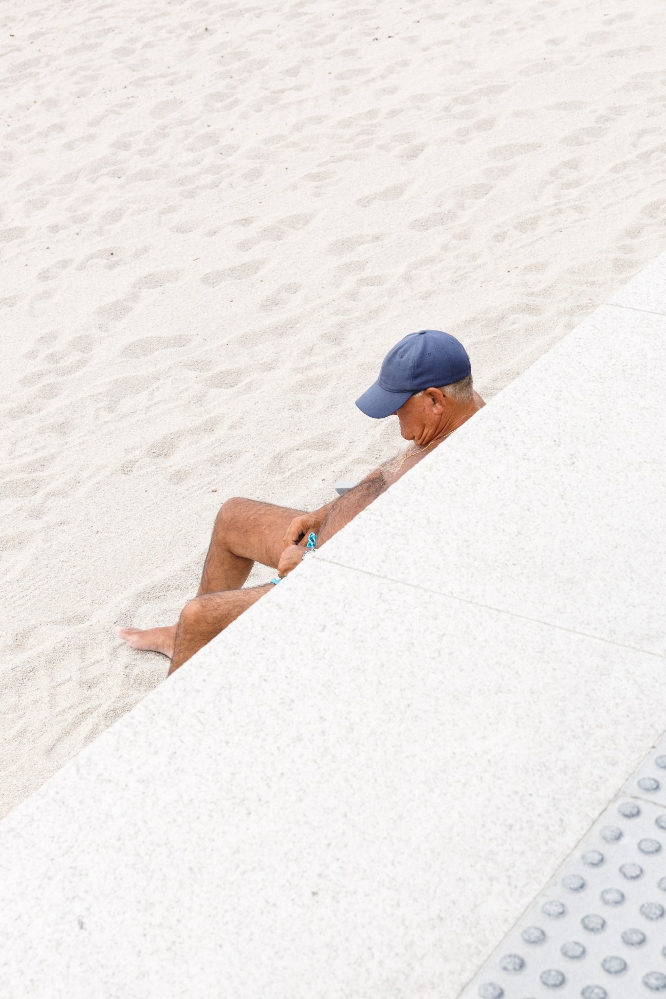Man in blue cap resting on white sand beach in A Coruña.