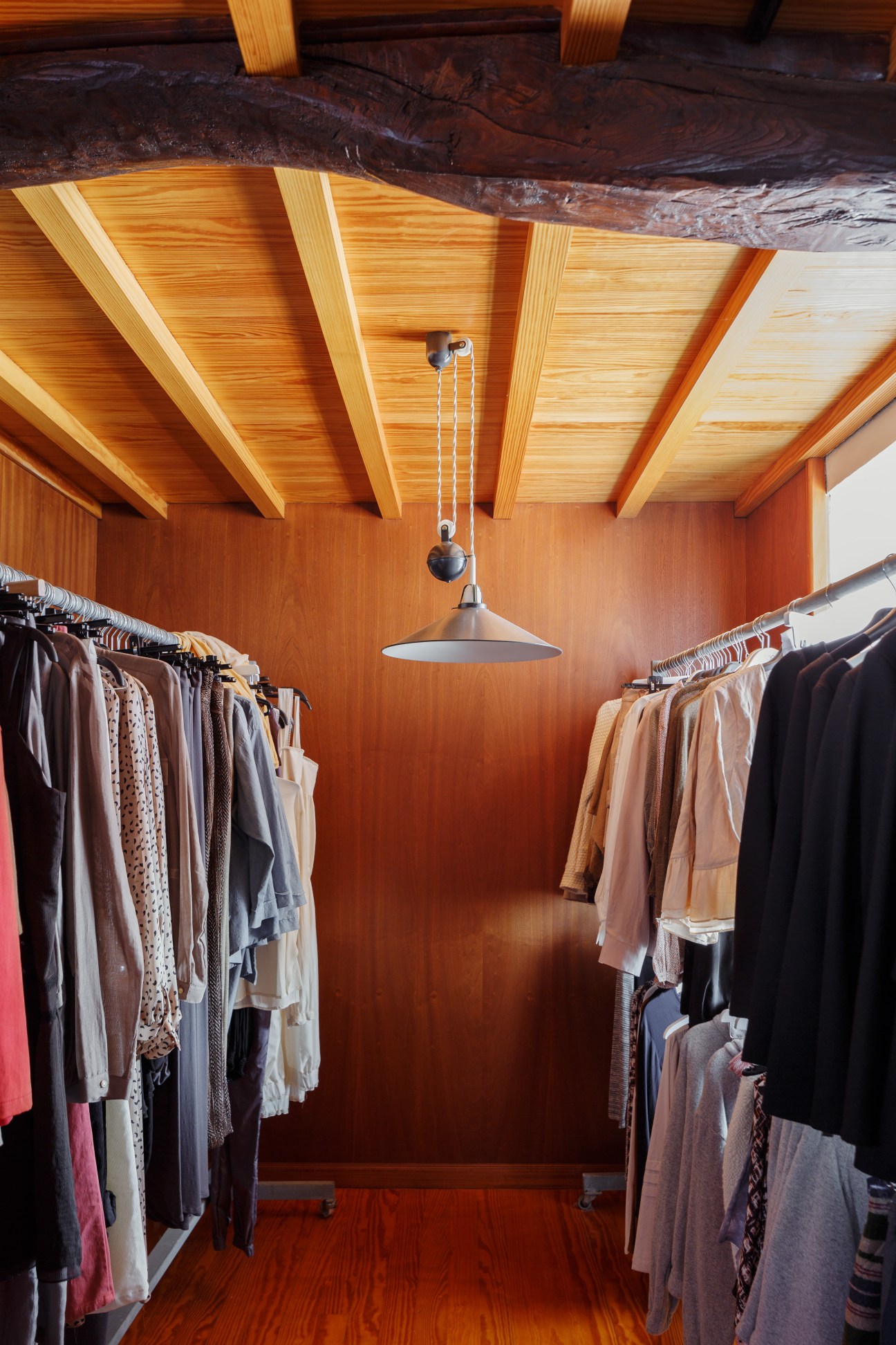 Interior of Poe boutique with wooden ceiling and clothing racks displaying garments.