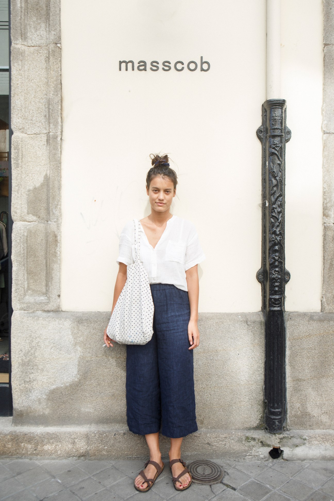 Woman posing outside Masscob storefront wearing white shirt and navy culottes