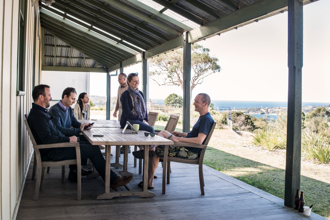 Team from Headland Capital working at an outdoor table with Sydney Harbour views.
