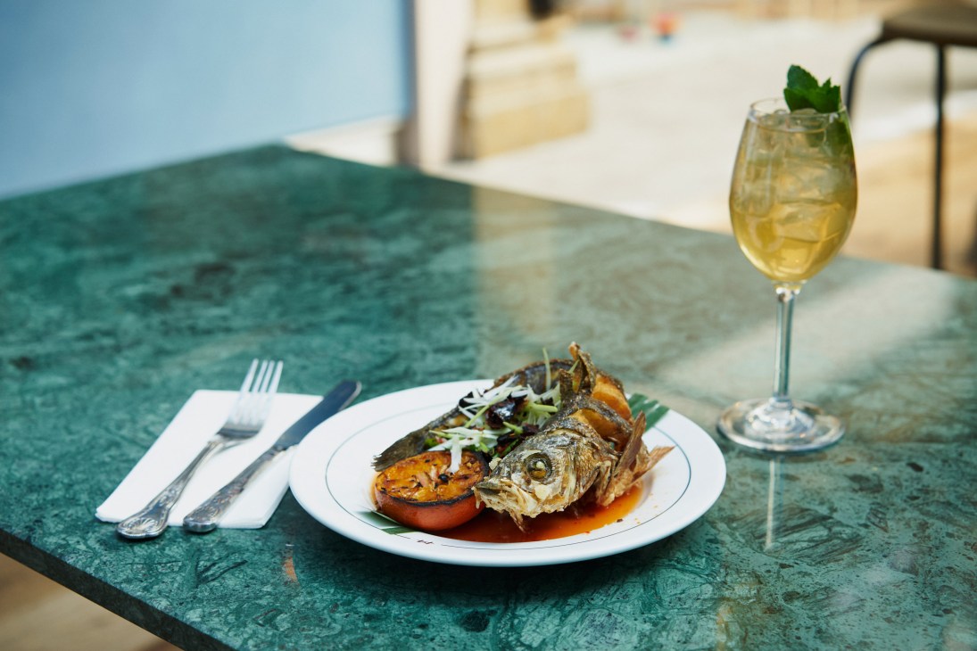 Whole crispy seabass plated at Farang with a Fulham Spritz cocktail on a teal table.