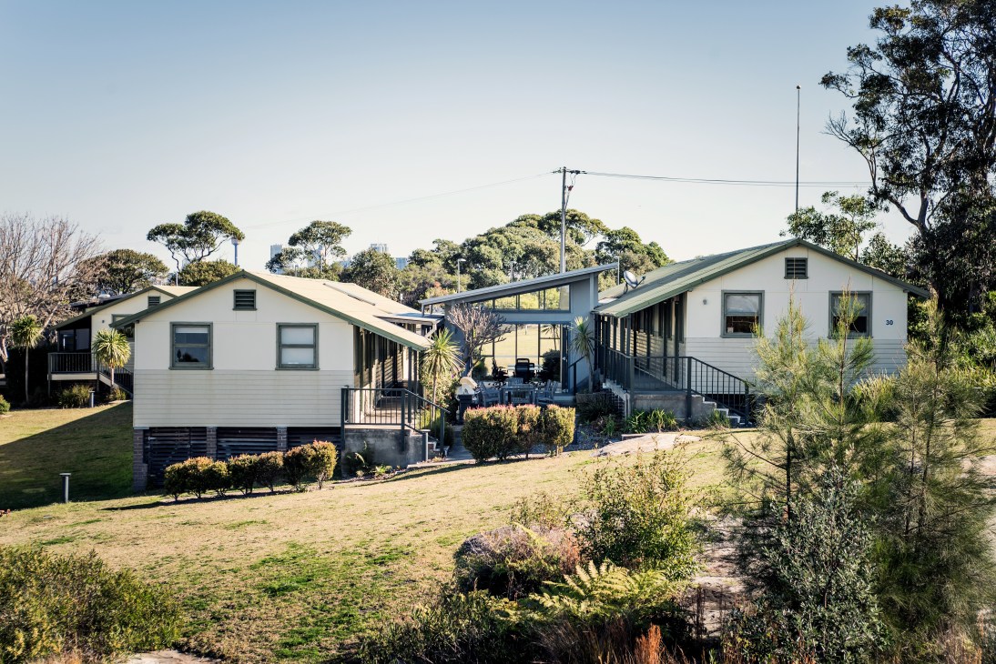 White converted military hut buildings with green roofs at Headland Park in Sydney, surrounded by landscaping and trees.