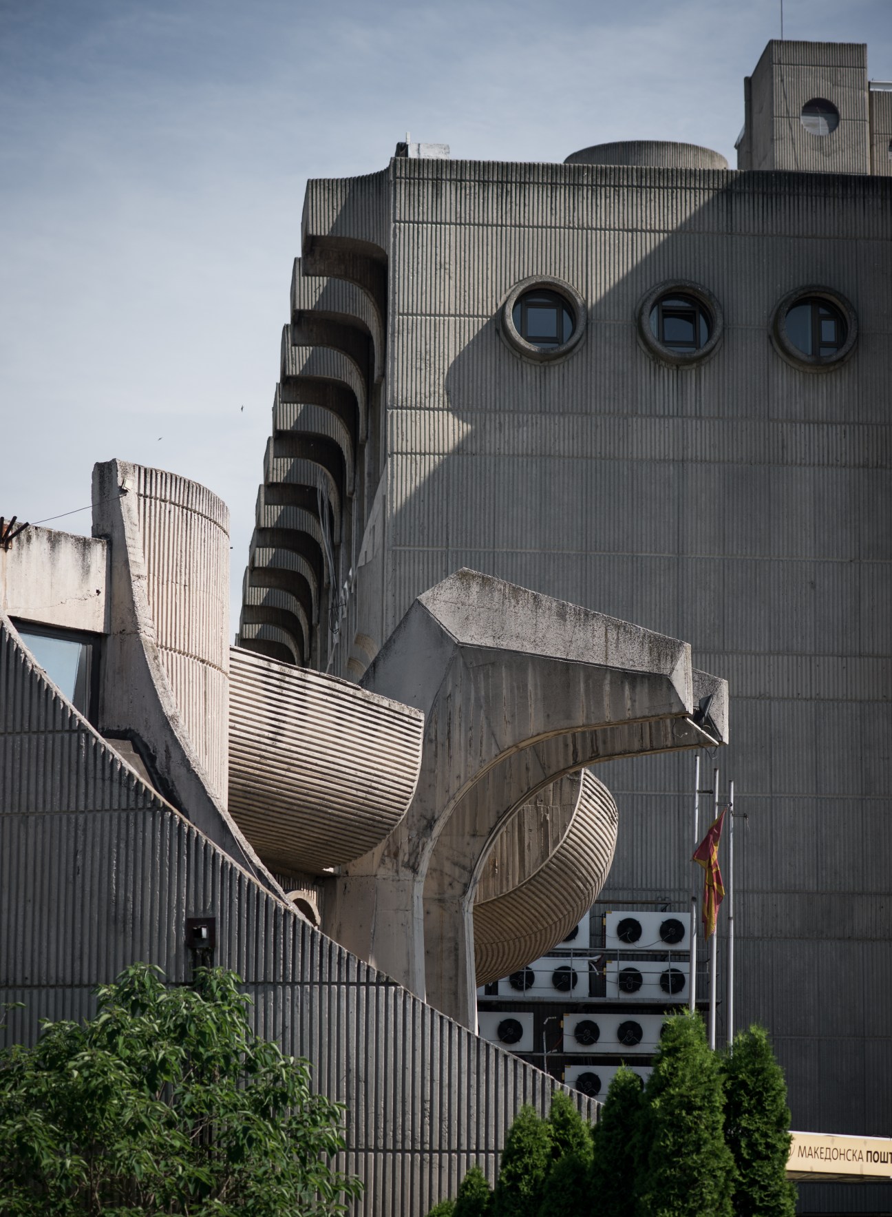 Brutalist concrete post office building with curved spiral staircase and circular windows designed by Kenzo Tange.