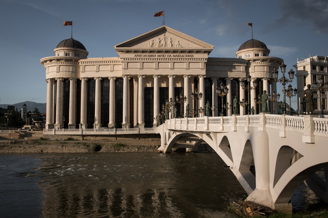 Neoclassical archaeological museum building with columns and dome reflected in the Vardar river, Skopje.