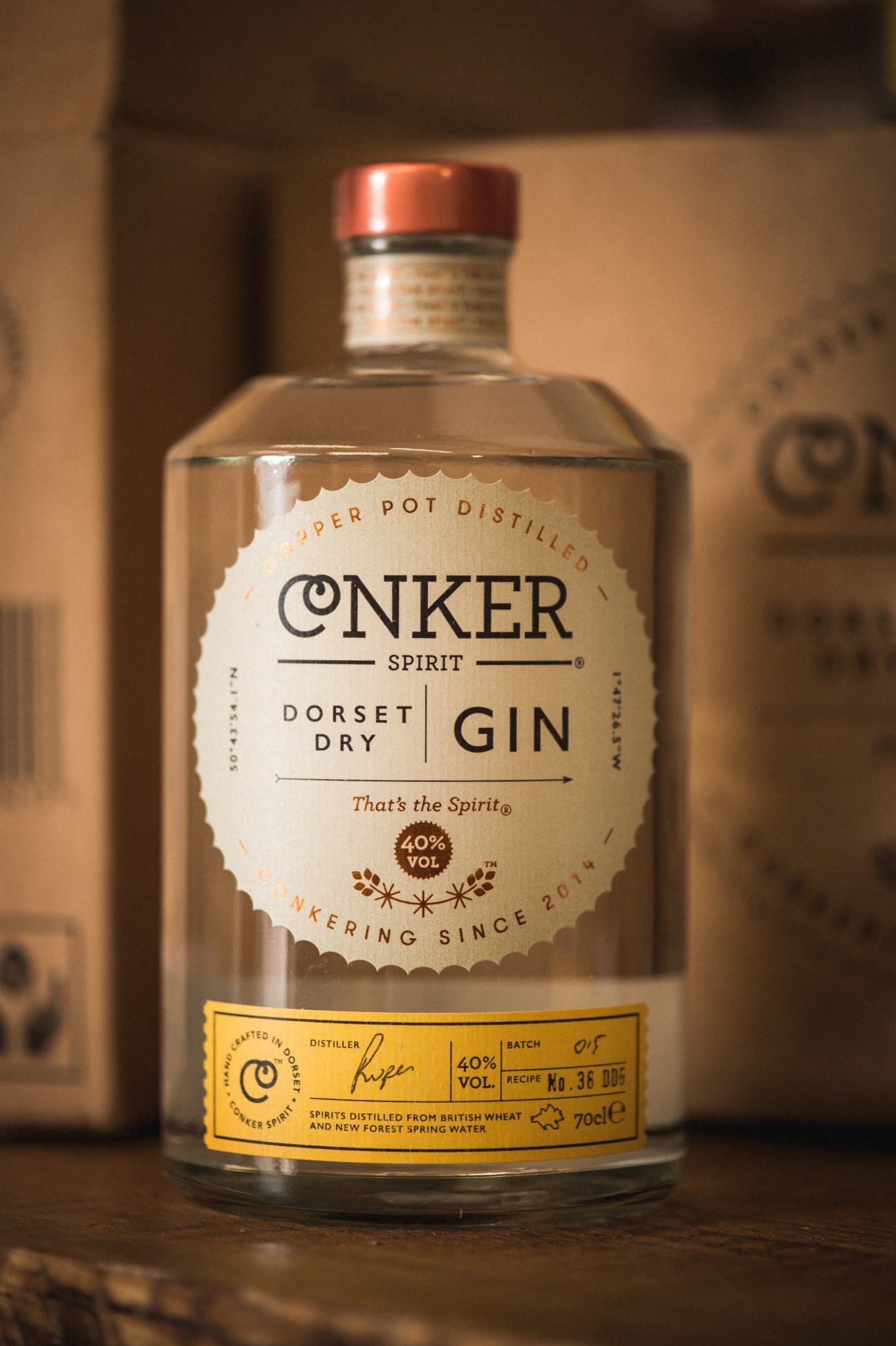 Conker Spirit Dorset Dry Gin bottle with copper cap and cream label on wooden surface.