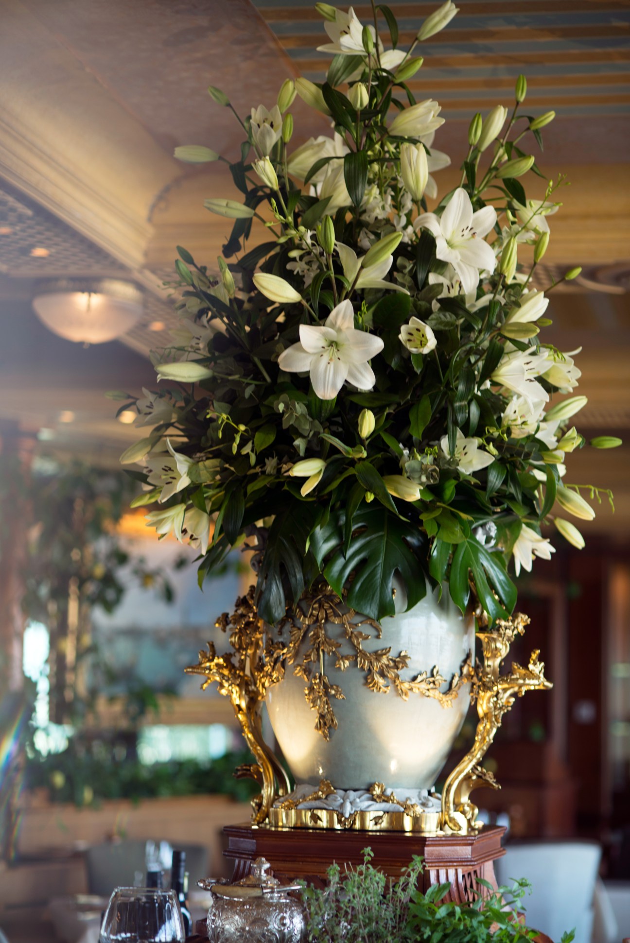 White lilies in an ornate gold and white vase at La Pergola restaurant.