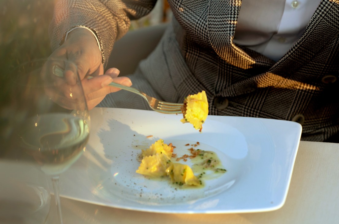 A fork lifts a piece of fagottini pasta from a white plate during a meal at La Pergola restaurant.