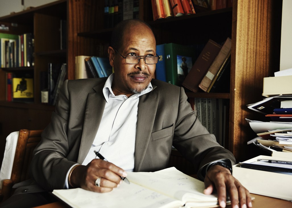 Ali Moussa Iye, chief of History and Memory for Dialogue Section, seated at his desk surrounded by books and papers.