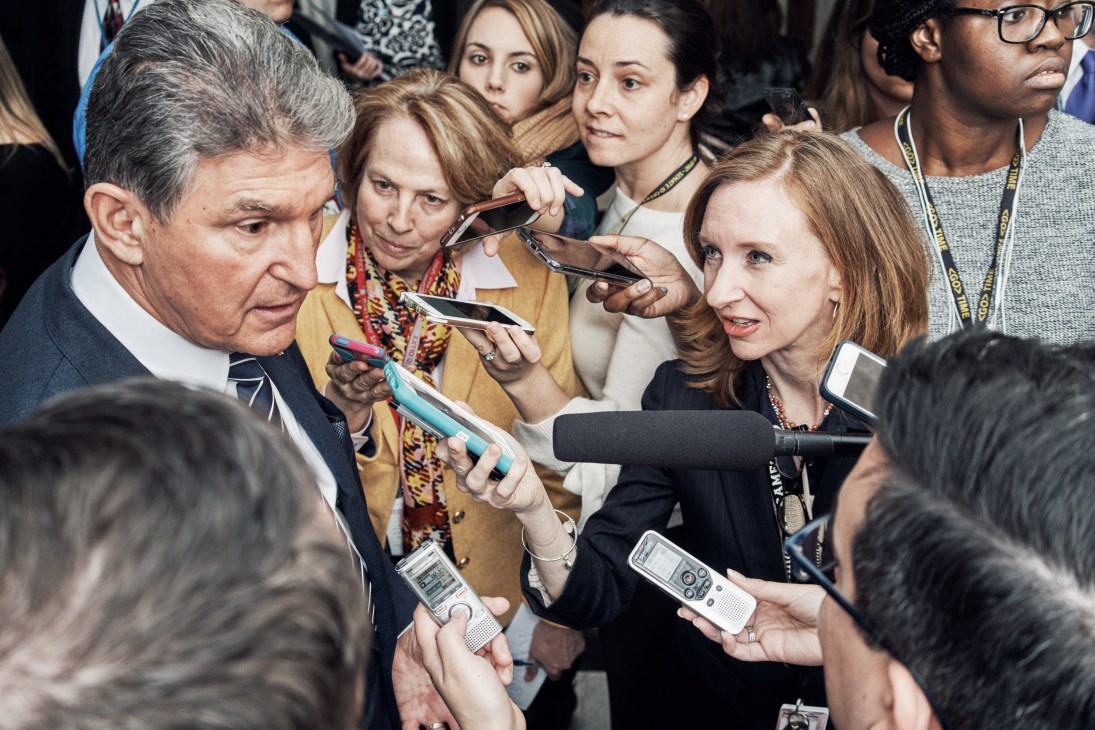 Political correspondent Lisa Desjardins interviewing Senator Joe Manchin outside the US Senate Chamber with microphones.