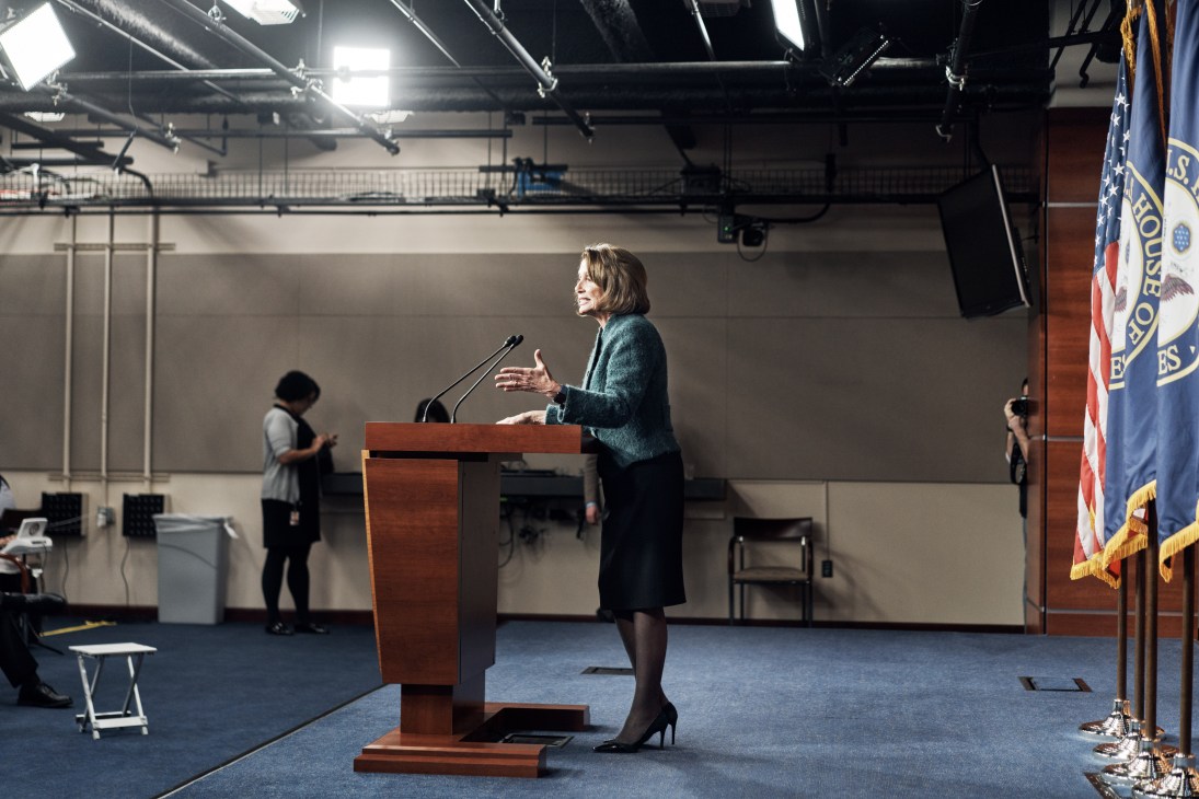 Congresswoman Nancy Pelosi speaking at a podium with microphones during a press conference.