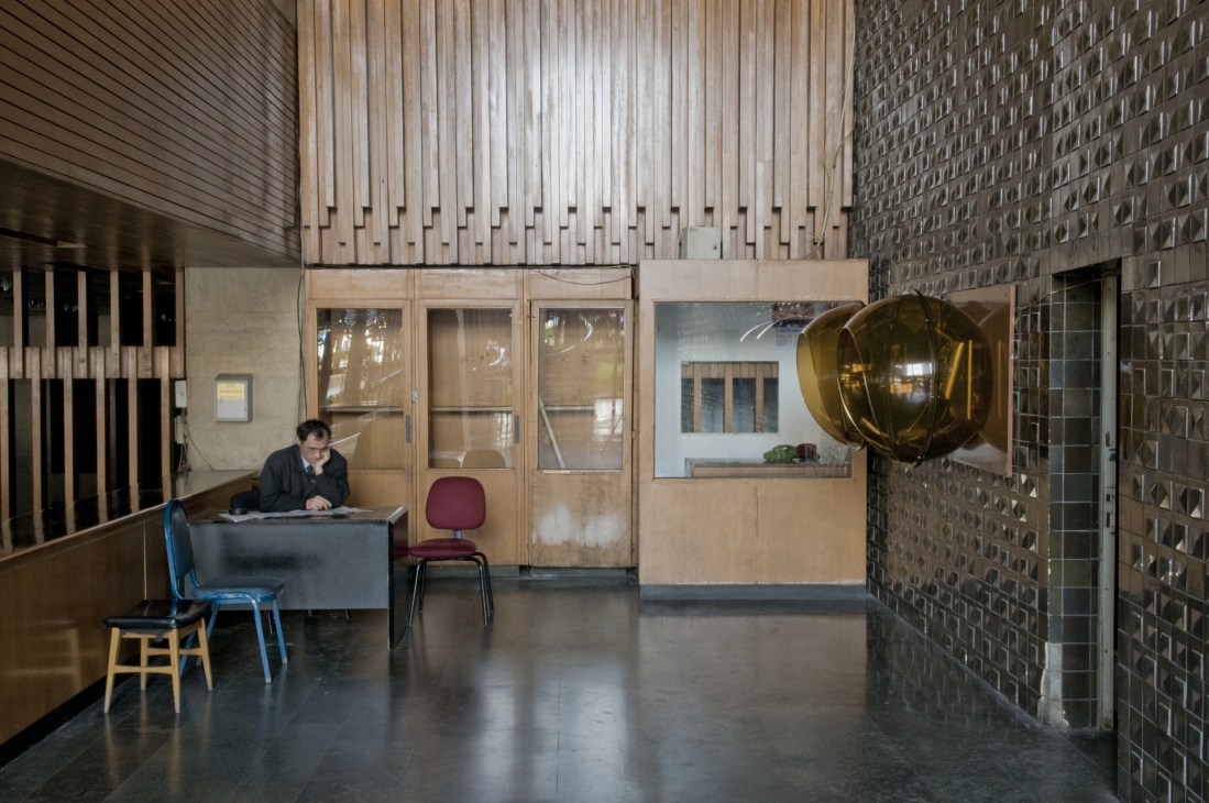 A janitor sits at a desk in the modernist entrance hall of the Atatürk Cultural Centre.