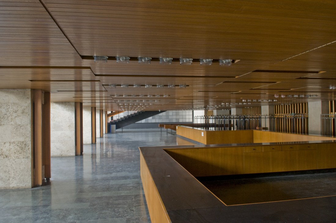 Interior of AKM's oak-panelled cloakroom with wooden counters and modernist architectural design.
