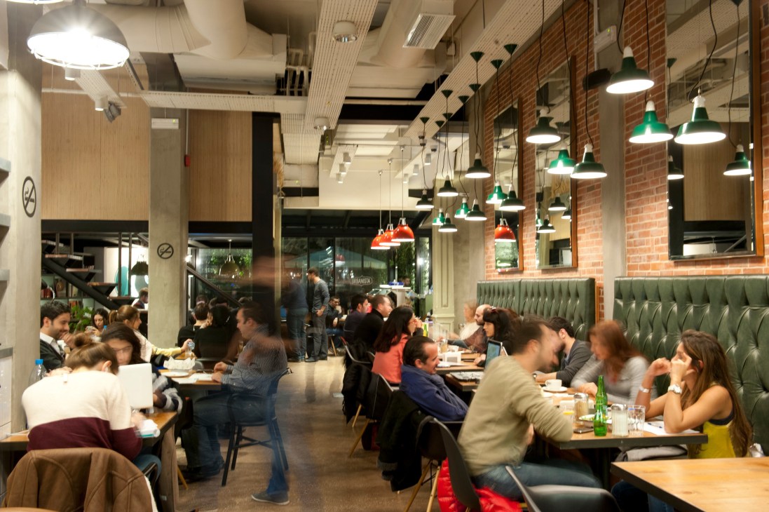 Interior of Urbanista restaurant in Beirut showing diners at tables with pendant lighting and brick walls.