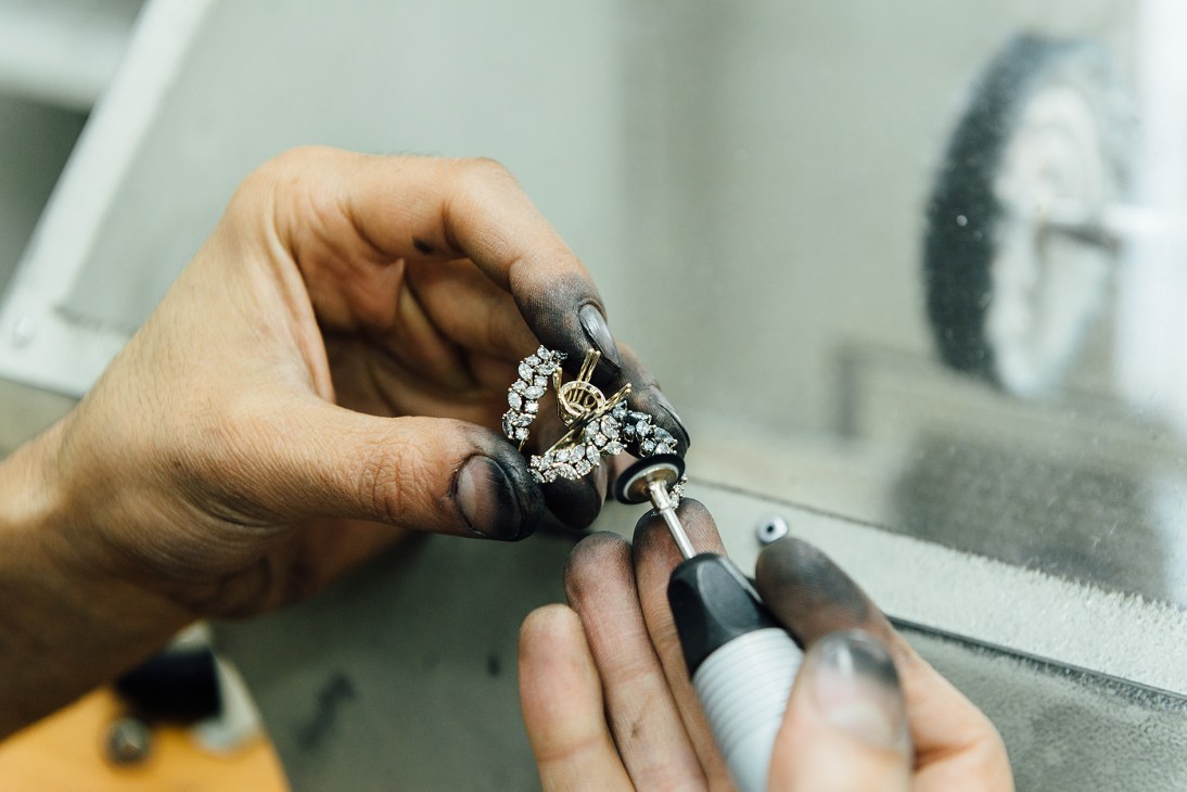 Jeweller's hands setting diamonds into a silver ring with precision tools.