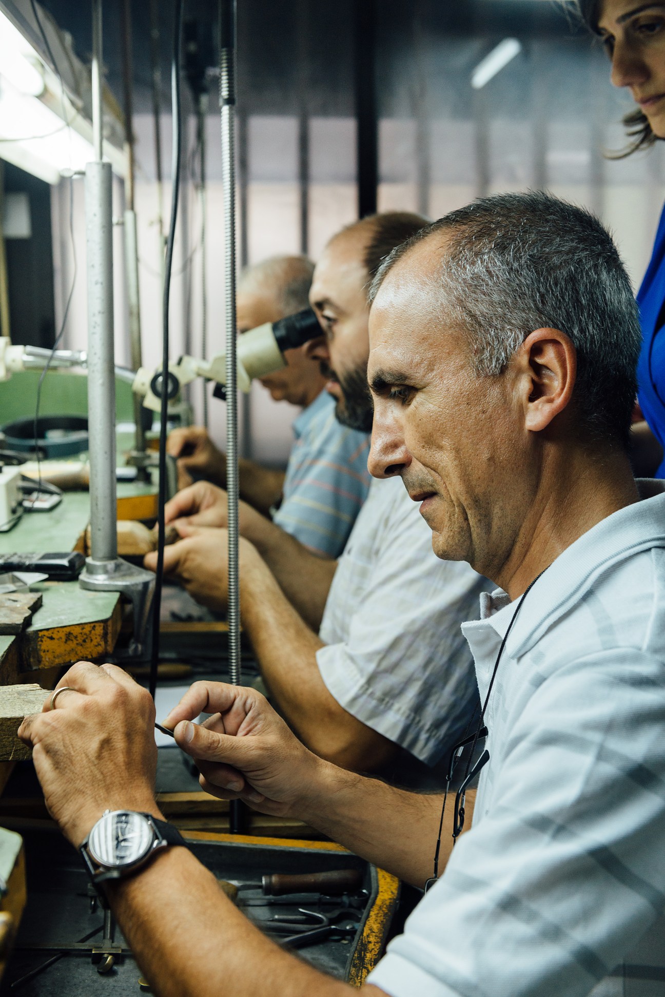 Armenian jewellers crafting fine jewellery at workbenches with precision tools and lighting in a workshop.