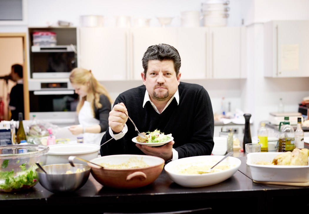 Jan Spielhagen, editor in chief of Essen & Trinken magazine, tasting food in a test kitchen surrounded by bowls and ingredients.