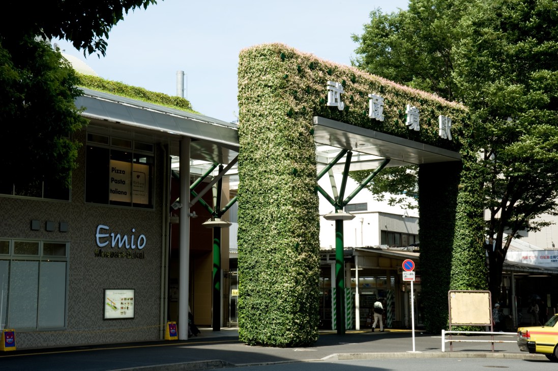 Vertical garden columns covered in dense green foliage frame the entrance to a station building.