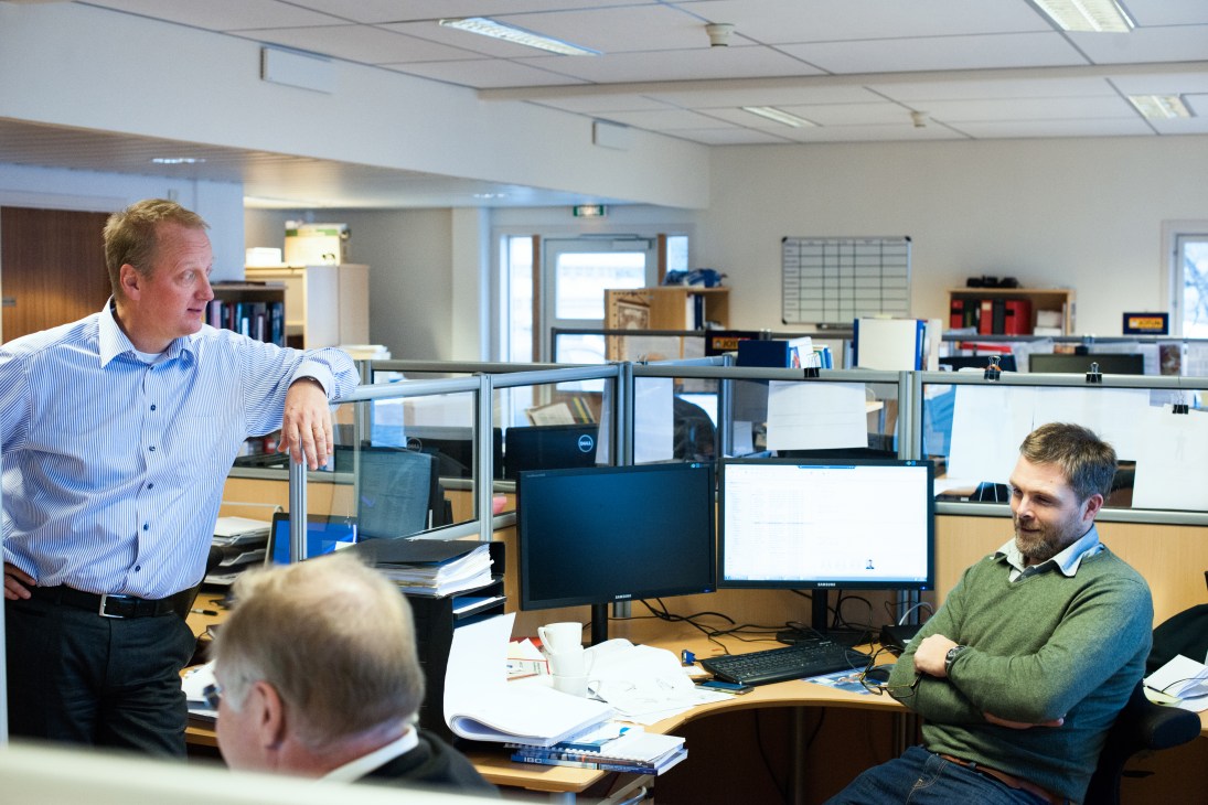 OSM Maritime Group office with employees working at desks with dual monitors in an open-plan workspace.