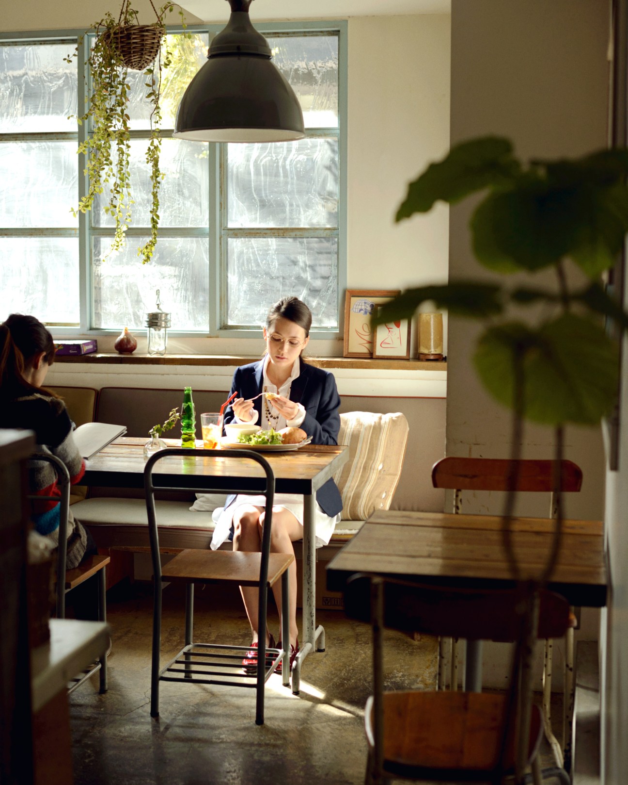 Woman in Effe Beams jacket and Gallego Desportes dress eating brunch alone at a café table.
