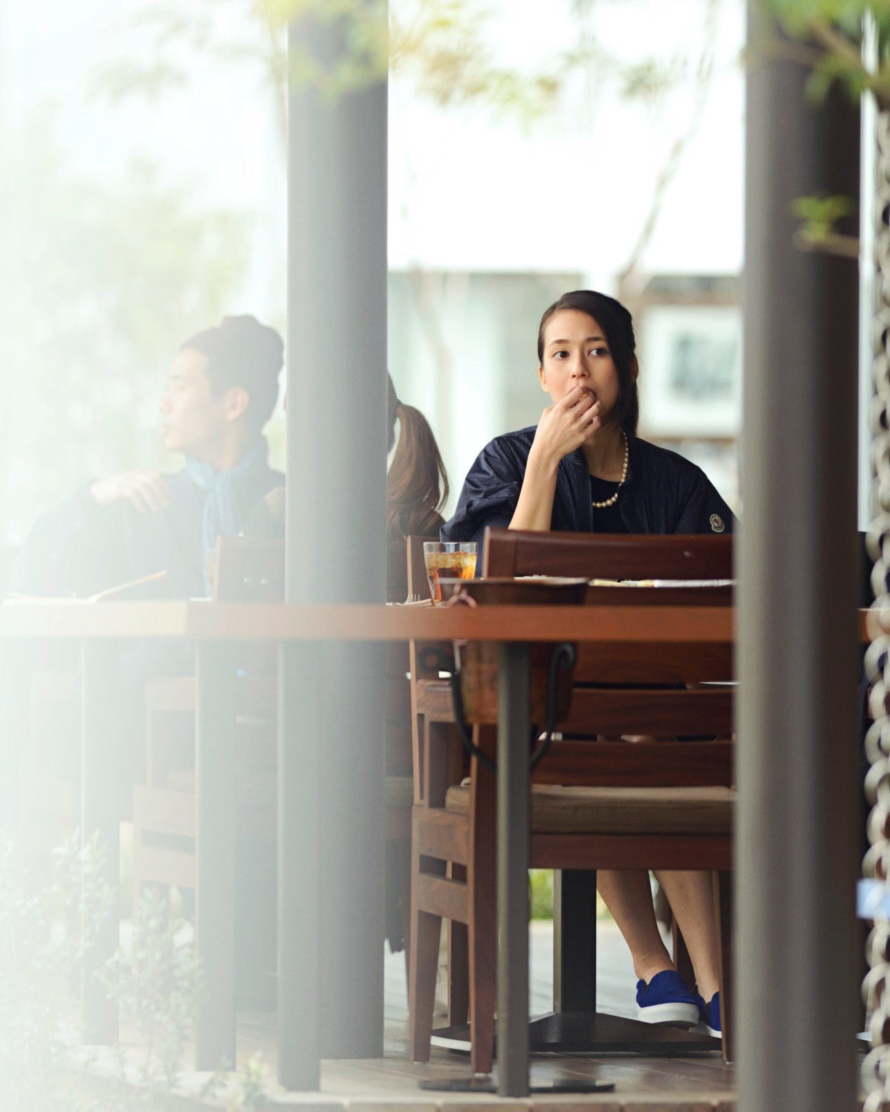 Woman in navy Moncler jacket and Lapis Luce dress seated at a Tokyo café counter with a drink.