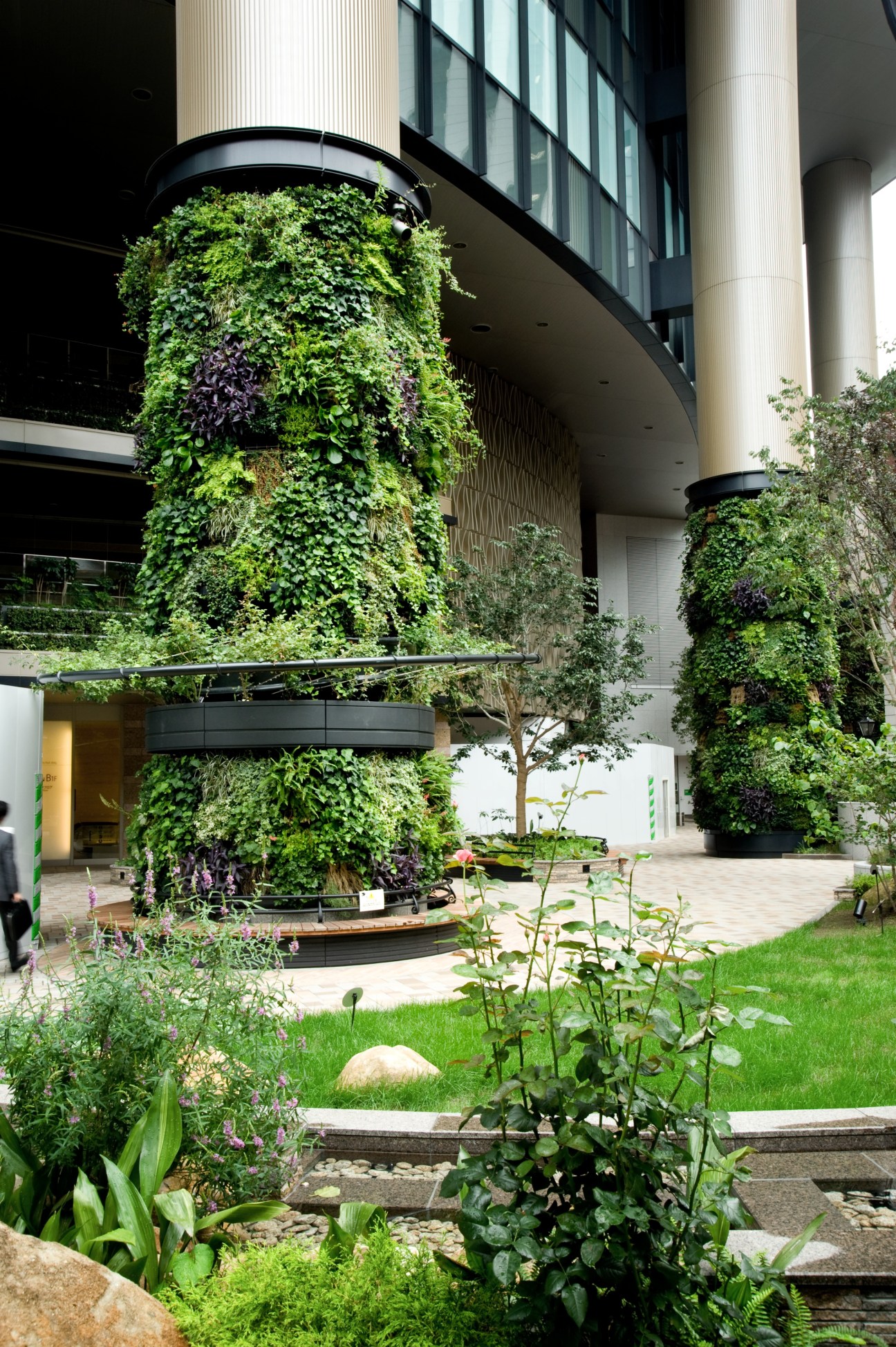 Tall cylindrical column covered in lush green foliage at Marunouchi Park Building in Tokyo