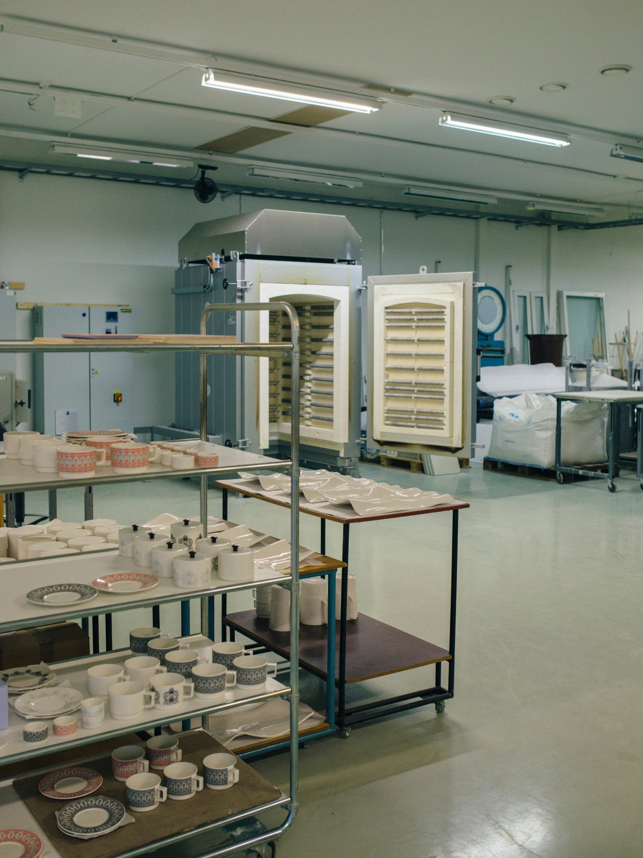 Vaja Finland's production facility showing ceramic dishware and tableware in various stages of manufacturing.