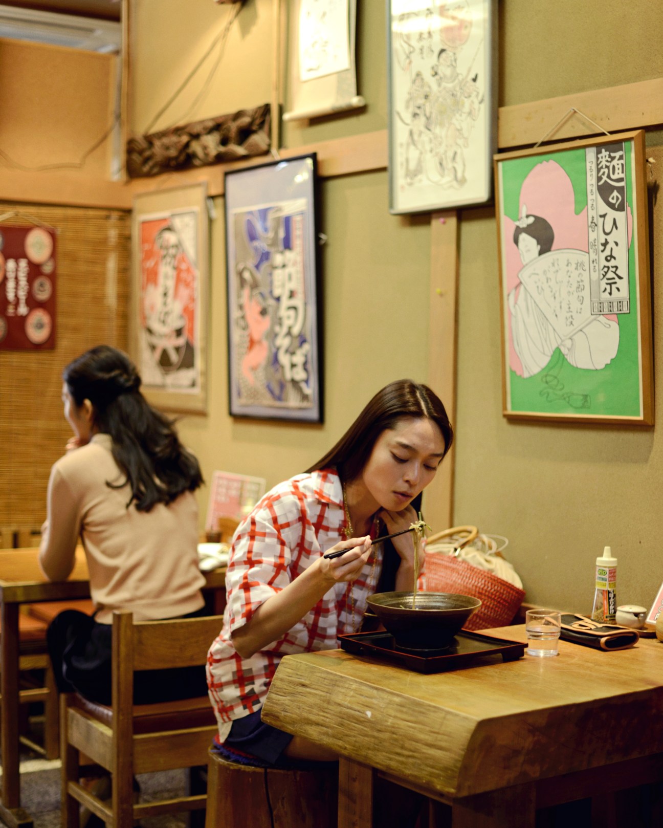 Woman in Marni top and United Arrows shorts eating soba noodles at Yabu Chu restaurant in Tokyo.