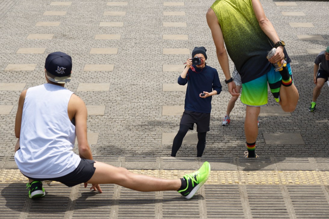 Yuito Ueda photographs runners on a paved street during a daytime shoot.