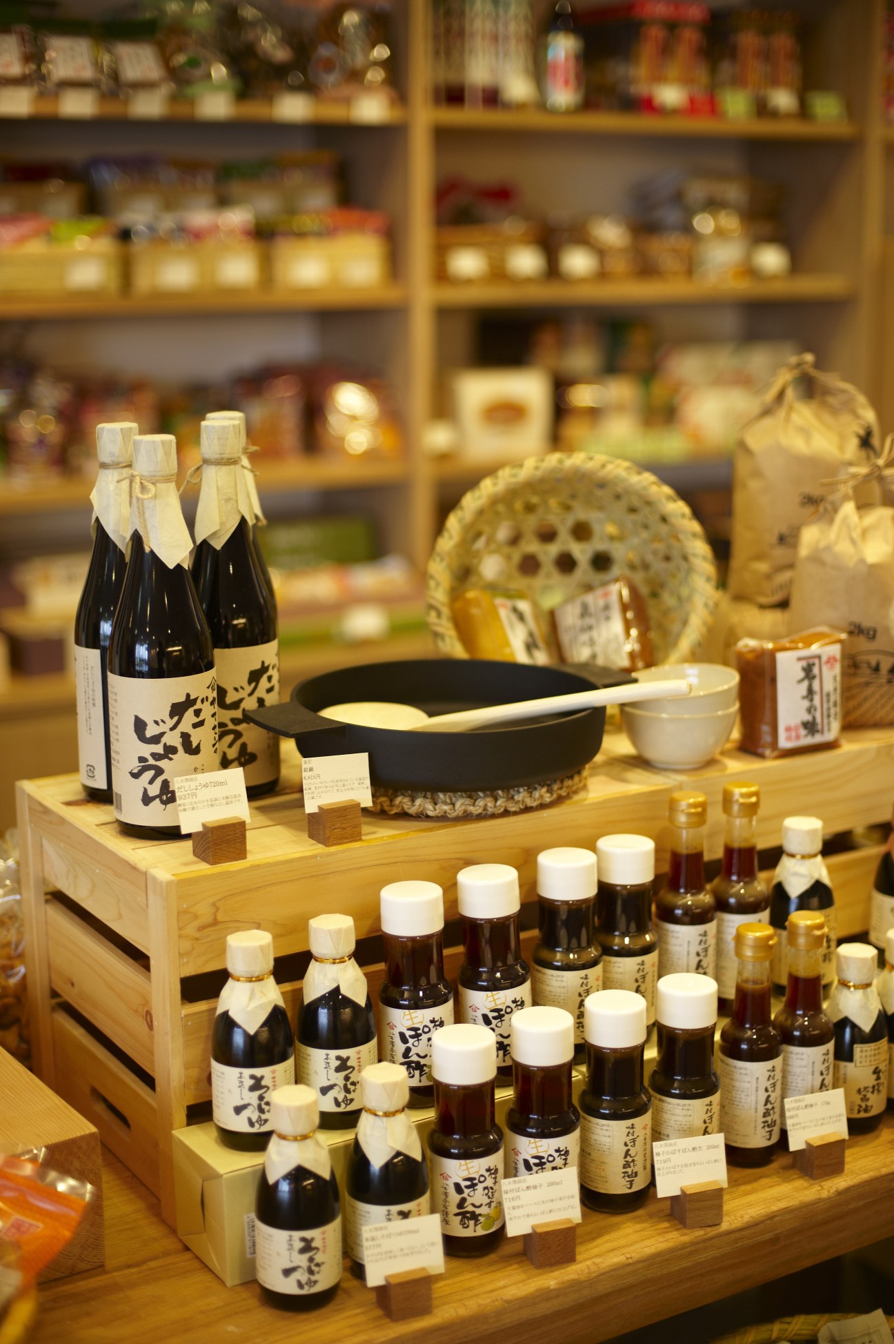 Display of Japanese condiments and cooking ingredients with bottles and bowls on wooden shelves.